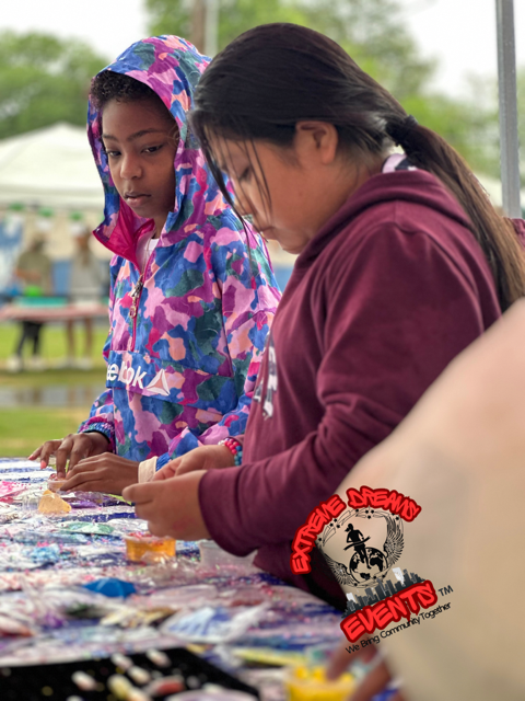 Two people sort items on a table at an outdoor event